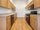 Galley kitchen with wood floor, black appliances, granite counters, and wood cabinets at 8985 S Durango Dr # 2081, Las Vegas, NV 89113