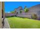 Landscaped backyard with artificial grass, tall walls for privacy, and string lights at 10142 Skye Saddle Ave, Las Vegas, NV 89166