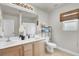 Bright bathroom with double sink vanity, toilet, woven shade, and large mirror, offering a serene atmosphere at 10392 Smokemont Ct, Las Vegas, NV 89129