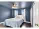 A bedroom with blue walls, a ceiling fan, and a comfortable bed with a patterned blue comforter at 10392 Smokemont Ct, Las Vegas, NV 89129