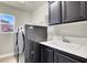 Laundry room with modern washer and dryer units, a utility sink, dark cabinets and a window at 10392 Smokemont Ct, Las Vegas, NV 89129