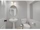 A modern powder room with a pedestal sink, a round mirror, and a water closet at 11009 Pentland Downs St, Las Vegas, NV 89141