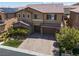 Charming two-story home with a well-manicured lawn, lush landscaping, and a spacious paver driveway leading to a three-car garage at 12296 Kings Eagle St, Las Vegas, NV 89141