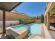 Inviting backyard pool featuring a tanning ledge, jacuzzi, and a tranquil water feature against a brick wall at 12296 Kings Eagle St, Las Vegas, NV 89141