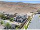 Aerial view of a two-story home with a tile roof and three-car garage situated in a desert community at 12705 Coastline Shadow St, Las Vegas, NV 89141