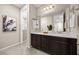 Bathroom featuring double sinks, dark wood vanity, and framed mirror with modern light fixture at 12705 Coastline Shadow St, Las Vegas, NV 89141