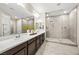 Bright bathroom featuring a double sink vanity, an oversized mirror, and a glass-enclosed shower with dual shower heads at 12705 Coastline Shadow St, Las Vegas, NV 89141