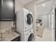 Convenient laundry room featuring stacked washer and dryer, plus granite countertop at 12705 Coastline Shadow St, Las Vegas, NV 89141