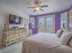 Bright main bedroom featuring a ceiling fan, wall-mounted television, framed wall art, and double doors to the backyard at 15 Avenza Dr, Henderson, NV 89011