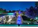 Stunning backyard featuring a long pool, lush landscaping, and vibrant lighting, perfect for evening relaxation and entertainment at 2323 Pinto Ln, Las Vegas, NV 89107