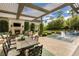 Inviting outdoor patio with dining area, fireplace, lush landscaping, and view of the pool at 2323 Pinto Ln, Las Vegas, NV 89107