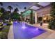 A luxurious backyard pool includes a covered patio, stone features, vibrant lighting, and lush landscaping at 2323 Pinto Ln, Las Vegas, NV 89107
