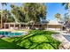 Expansive backyard featuring lush artificial grass, large tree, covered patio, and inviting pool at 2617 Mason Ave, Las Vegas, NV 89102