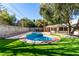 Landscaped backyard featuring artificial turf, a mature tree, and a sparkling in-ground pool for outdoor enjoyment at 2617 Mason Ave, Las Vegas, NV 89102