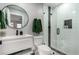 Modern bathroom featuring a sleek vanity, round mirror, and a glass-enclosed shower with white subway tile and dark fixtures at 2617 Mason Ave, Las Vegas, NV 89102