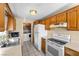 Bright kitchen with wooden cabinets, appliances, tile floor, and a designated area for a washer and dryer at 2821 Geist Cir, Las Vegas, NV 89115