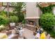 Cozy outdoor living space with a stone fireplace, comfortable seating, and lush surrounding greenery at 517 Spruce Canyon St, Las Vegas, NV 89144