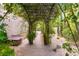 Serene backyard pathway with a lush pergola, mature trees, and manicured landscaping, creating a private garden retreat at 517 Spruce Canyon St, Las Vegas, NV 89144