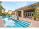 Stunning pool area with a tanning ledge, clear blue water, a covered patio, and a lush backyard with mature trees at 517 Spruce Canyon St, Las Vegas, NV 89144