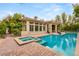 Inviting backyard oasis featuring a sparkling pool, a relaxing hot tub, a lush lawn, and a covered patio at 517 Spruce Canyon St, Las Vegas, NV 89144