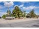 Home exterior with desert landscaping, mature trees, and ample parking on a quiet street at 5180 N Dapple Gray Rd, Las Vegas, NV 89149