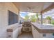 Covered outdoor kitchen boasts a built-in grill and tiled countertops, perfect for entertaining by the pool at 5180 N Dapple Gray Rd, Las Vegas, NV 89149