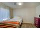 Simple bedroom with bed, striped throw blanket, floral decorated dresser, and neutral walls at 533 Date St, Boulder City, NV 89005