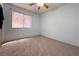 This bedroom offers neutral walls, carpet, a window, and a ceiling fan at 5638 Morning Song Cir, North Las Vegas, NV 89031