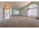 Bright living room with neutral carpet, chandelier, and large windows with light-filtering curtains at 5638 Morning Song Cir, North Las Vegas, NV 89031