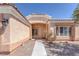 View of front entrance featuring covered front porch, tiled roof trim, tan walls, desert landscaping, and shuttered windows at 5808 Spinnaker Reach Ave, Las Vegas, NV 89130