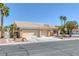 Charming single-story home featuring a three-car garage and desert landscaping with palm trees under a clear blue sky at 5808 Spinnaker Reach Ave, Las Vegas, NV 89130