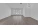 Open living room with fresh white walls, grey wood floors, modern lighting, and windows with privacy shutters at 5808 Spinnaker Reach Ave, Las Vegas, NV 89130
