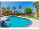 Backyard view featuring a freeform pool with steps, palm trees, and mature landscaping at 7141 Groveton Ct, Las Vegas, NV 89131