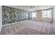 Spacious bedroom features a leafy accent wall, carpet, ceiling fan, and natural light from large windows at 7665 Serenity Bay Ln # Lot 58, North Las Vegas, NV 89084