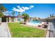Lush backyard with a pool, grassy area, and an outdoor covered area with a unique stone fireplace at 8340 W Fisher Ave, Las Vegas, NV 89149