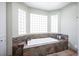 Relaxing soaking tub surrounded by decorative stonework and natural light from glass block windows at 8340 W Fisher Ave, Las Vegas, NV 89149