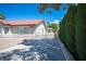 View of the side of the home featuring a terra cotta roof, stucco walls, and a tall green privacy hedge at 8340 W Fisher Ave, Las Vegas, NV 89149