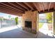 Outdoor covered fireplace made of decorative stone with a wood beam ceiling and view of the backyard pool at 8340 W Fisher Ave, Las Vegas, NV 89149
