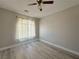 Bedroom with wood-look floors, neutral walls, a window with sheer curtains, and fan at 8717 Harvest Valley Ave, Las Vegas, NV 89129