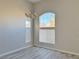 Bright living room with tall windows, chandelier, and gray wood-look floors at 8717 Harvest Valley Ave, Las Vegas, NV 89129