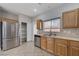 Well-lit kitchen featuring stainless steel appliances, tile countertops, wood cabinetry, and pantry at 9004 Snowtrack Ave, Las Vegas, NV 89149