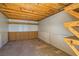 Unfinished basement with pegboard walls, plywood flooring, exposed wooden ceiling, and built-in shelving at 9208 November Breeze St, Las Vegas, NV 89123