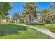 Well-manicured common area with lush green grass, mature trees, walking path and park benches on a sunny day at 9208 November Breeze St, Las Vegas, NV 89123