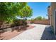 Paver patio in a backyard with a retaining wall planter, mature trees, and drought resistant rock at 9450 Niagara Landing St, Las Vegas, NV 89139