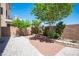 Paver patio in a backyard featuring mature trees, minimal landscaping, and a tan stucco wall at 9450 Niagara Landing St, Las Vegas, NV 89139