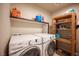 Bright laundry room with washer, dryer, and wooden shelf at 9450 Niagara Landing St, Las Vegas, NV 89139