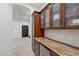 Butler pantry with mini fridge, granite counter, and wood cabinets with glass doors at , Las Vegas, NV 89135