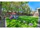 Beautifully landscaped backyard with artificial turf, mature trees, and a charming playhouse at 10213 Treasure Mountain Ct, Las Vegas, NV 89129