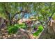 Home features a lush backyard with a playhouse, artificial turf, and mature trees at 10213 Treasure Mountain Ct, Las Vegas, NV 89129