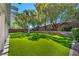 Well-maintained backyard features lush artificial grass, mature trees, and a charming playhouse at 10213 Treasure Mountain Ct, Las Vegas, NV 89129